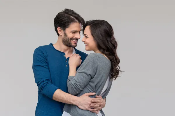 Erectile-Dysfunction-Doctor A man in a blue shirt embracing a woman in a gray shirt smiles due to his successful erectile dysfunction care from Fonthealth in Niagara.
