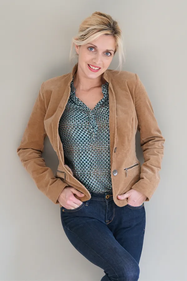 Metabolic-Syndrome-Treatment A smiling blonde woman in a tan leather jacket leans against a gray wall. Schedule metabolic syndrome from Fonthealth in Niagara.