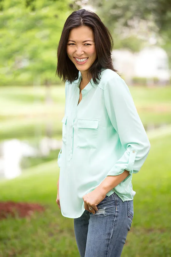 Perimenopause-Treatment A middle-aged brunette woman in a light green button-up shirt stands outside smiling, happy with her perimenopause treatment from Fonthealth in Niagara.