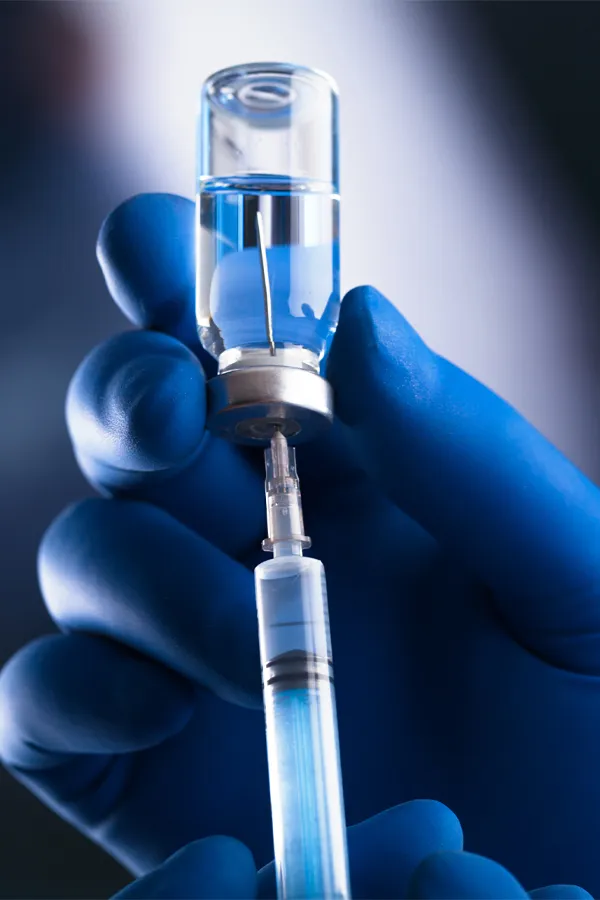 Regenerative-Under-Eye-PRP-treatment Close up of a hand in medical gloves drawing fluid from a vial with a syringe. Get PRP regenerative under eye treatment from Fonthealth in Niagara.