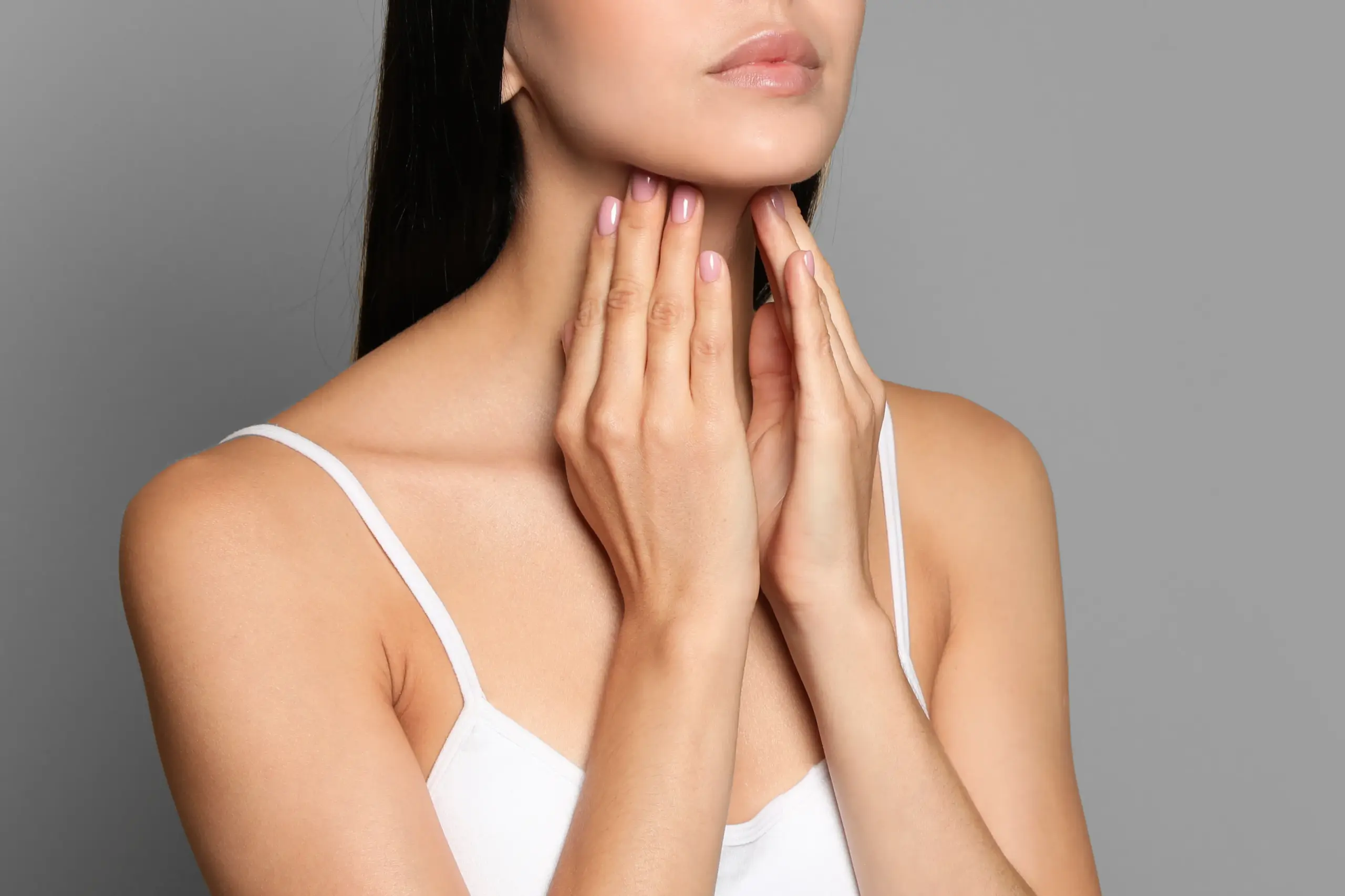 Thyroid-Doctor A woman in a white tank top touches her neck looking for signs of thyroid disorder. Get help for thyroid disorders from Fonthealth in Niagara.